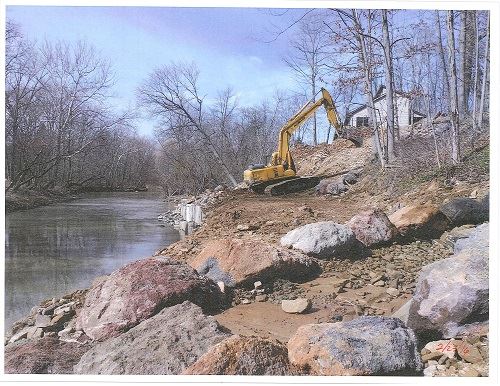 A bulldozer sits on a river embankment