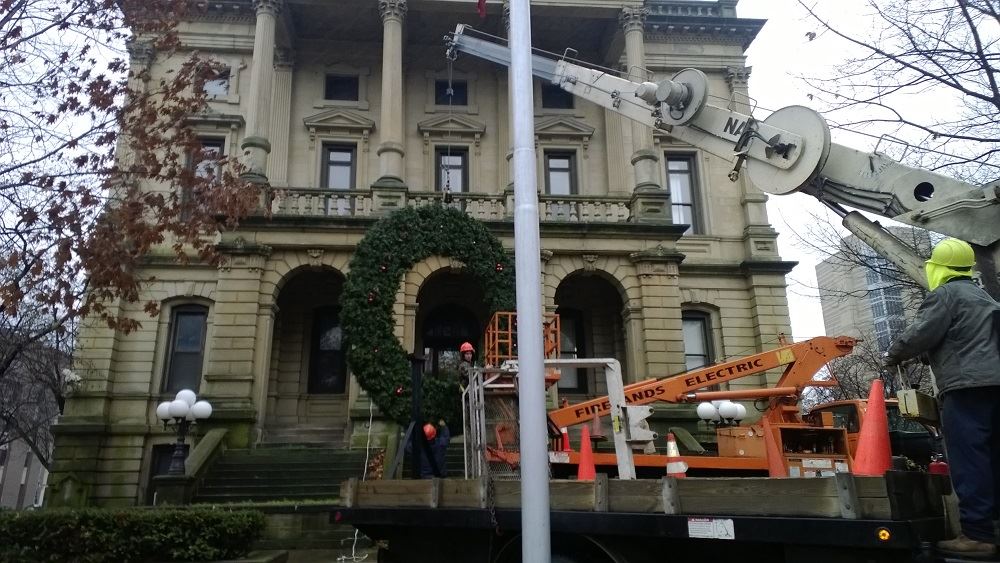 Hanging a large holiday wreath on a public building with a crane 3