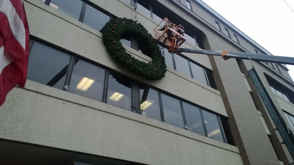 A large holiday wreath on the side of a public building